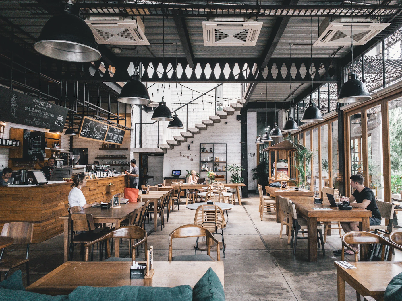 Sala luminoasă a unui restaurant cu mese din lemn